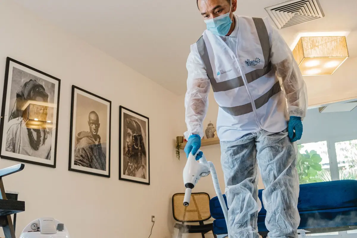 Technicien en combinaison et masque qui traite une pièce
