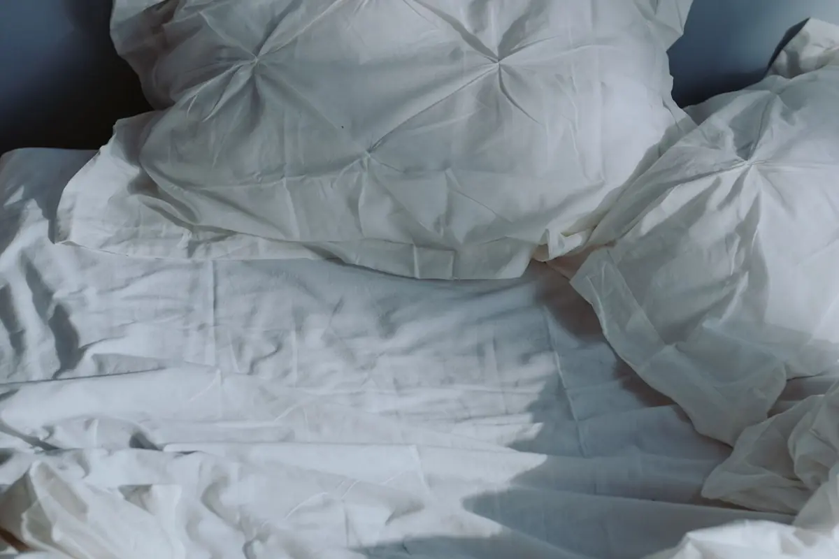 Lit défait aux draps blancs froissés
